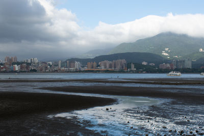 Sea by city buildings against sky