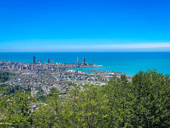 Scenic view of sea by buildings against blue sky
