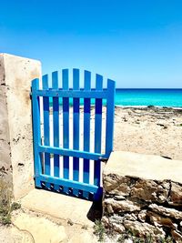 Deck chairs on beach against clear blue sky