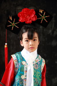 Portrait of girl wearing traditional clothing standing against wall