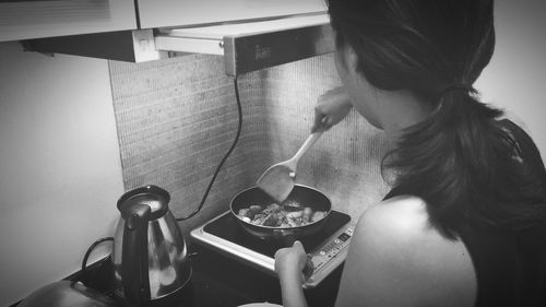 Rear view of woman cooking in kitchen at home