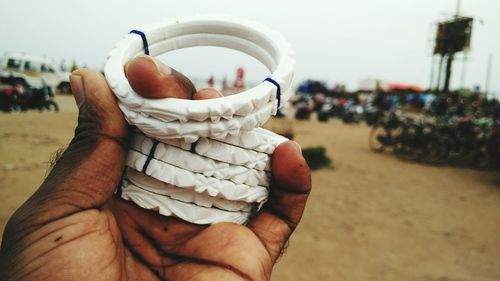 Cropped hand of man holding bangles at beach
