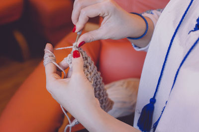 Midsection of woman knitting wool at home