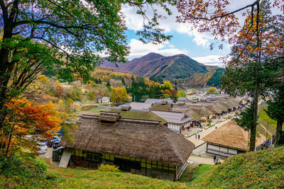 Houses and trees by mountain against sky during autumn