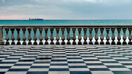 Row of railing by sea against sky