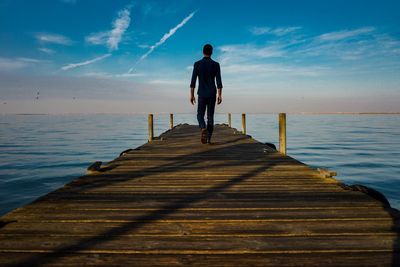 Rear view of man walking on jetty