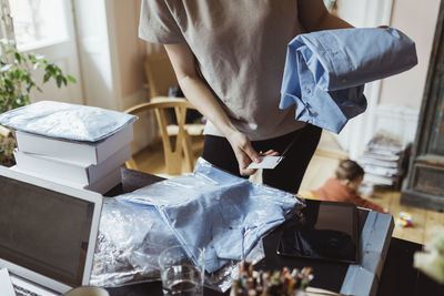 Midsection of businesswoman holding shirt while standing in living room