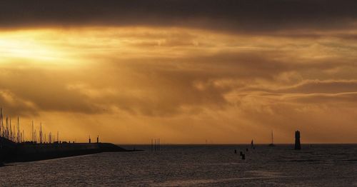 Silhouette sailboats in sea against sky at sunset