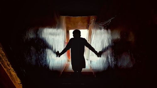 Rear view of silhouette man standing in corridor