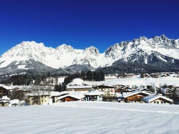 Houses on snowcapped mountains against clear blue sky