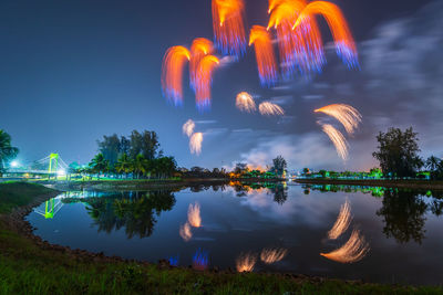 Firework display over lake against sky