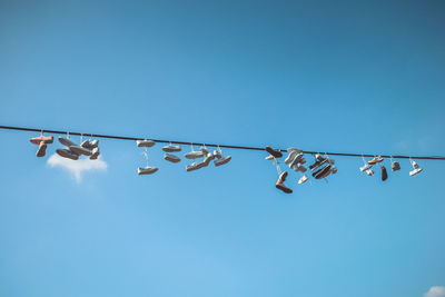 Low angle view of flags hanging against clear blue sky