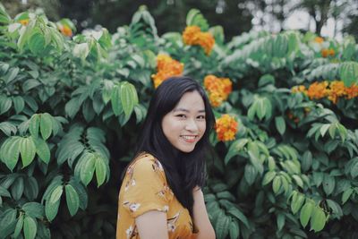 Portrait of smiling woman by plants