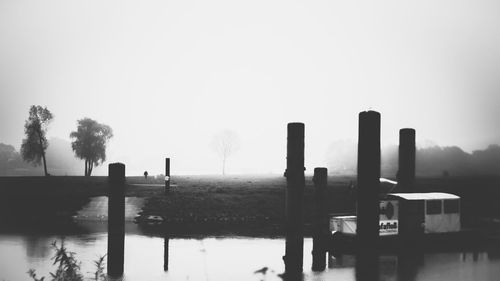 Wooden posts in lake against clear sky