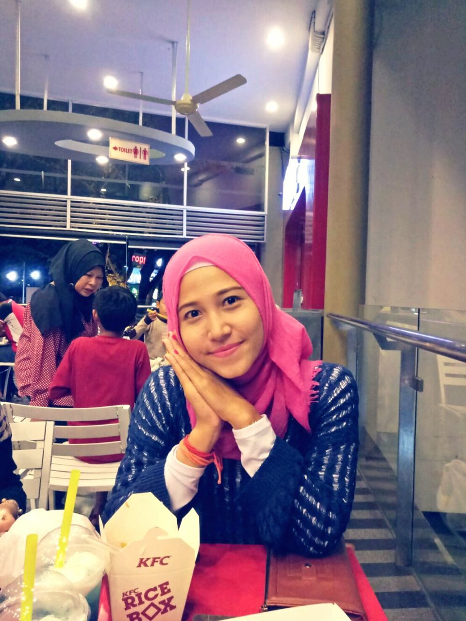 PORTRAIT OF SMILING WOMAN SITTING IN RESTAURANT AT NIGHT