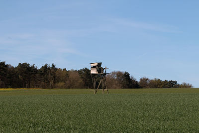 Lifeguard hut on field against blue sky