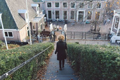 Rear view of woman walking down steps in city