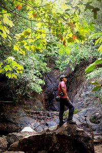 Full length of man standing on rock in forest