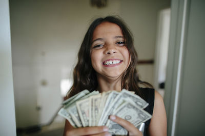 Portrait of cheerful girl with paper currency at home