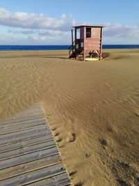 Lifeguard hut on beach against sky