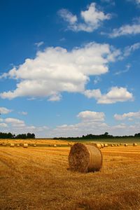 Hay bales on field against sky