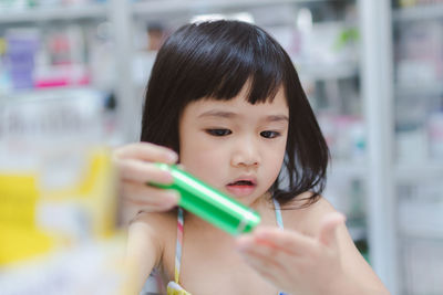 Close-up of girl holding flashlight at home