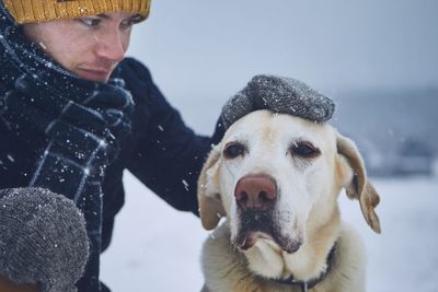 Man petting dog during snowy winter