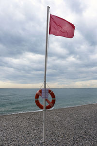 Close-up of red flag on beach against sky