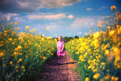 Portrait of girl standing on field against sky