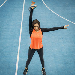 Full length of woman with arms raised at sports court