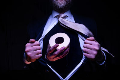 Midsection of man holding umbrella against black background