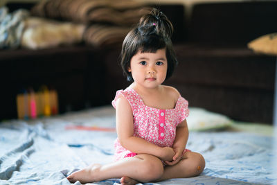 Portrait of cute girl sitting on bed