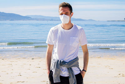 Man with medical mask in protection of the coronavirus in the new normal walking on the beach