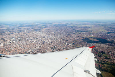 Aerial view of airplane wing over landscape against sky