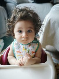 Portrait of cute baby girl sitting at home