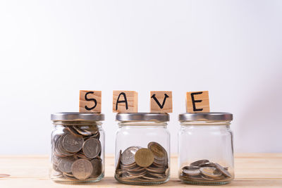 Close-up of coins in jar against white background