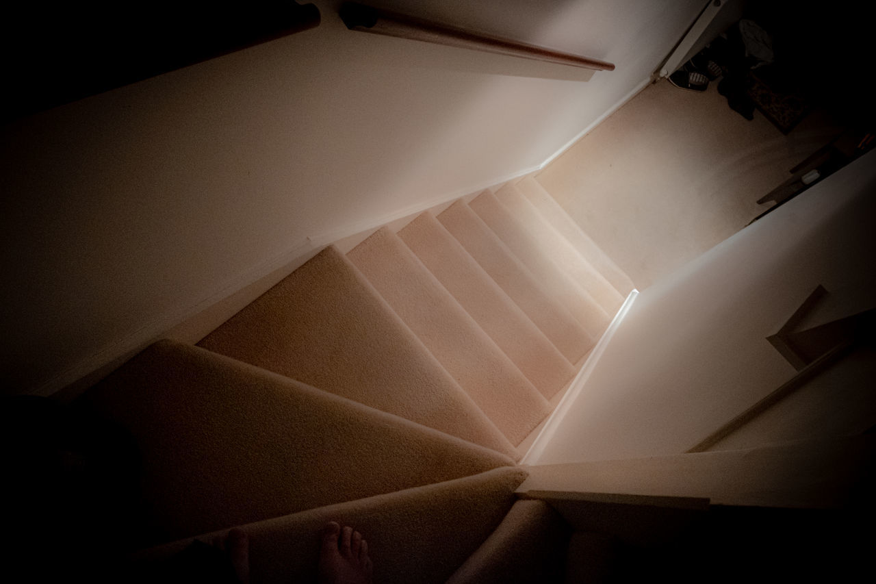 DIRECTLY BELOW SHOT OF ILLUMINATED STAIRCASE AT BUILDING