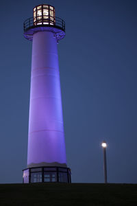 Low angle view of illuminated lighthouse against clear blue sky at dusk