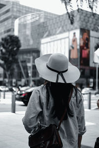 Rear view of woman with umbrella on street in city