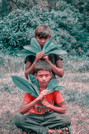 PORTRAIT OF FATHER WITH BABY SITTING ON PLANT