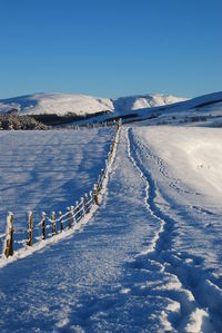 Scenic view of frozen landscape against clear blue sky