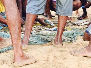 Low section of men standing on sand