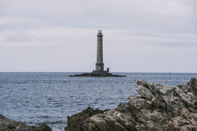 Lighthouse by sea against sky