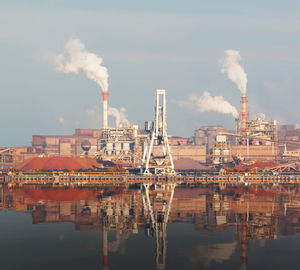 Smoke emitting from factory against sky