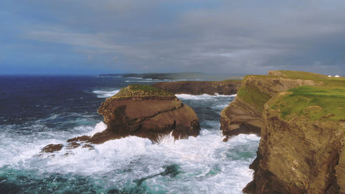 Rock formation on sea shore against sky