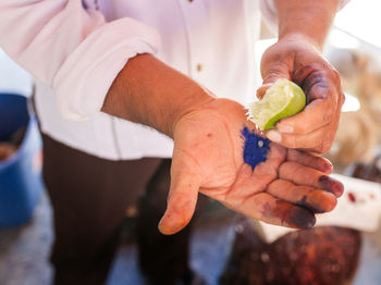 Midsection of man squeezing lemon on powder paint