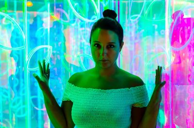 Portrait of woman standing against illuminated wall