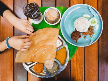 High angle view of woman holding food on table