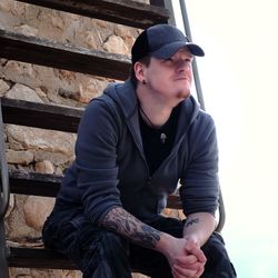 Young man looking away while sitting on steps