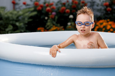 Portrait of a funny white 5-6-year-old child in swimming glasses with disheveled hair in the pool. 